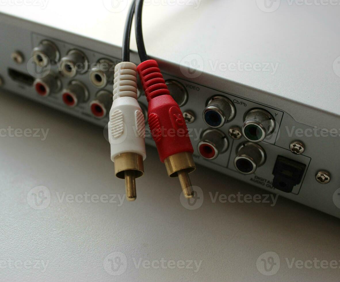 Rear panel of a multimedia player with connection slots and disconnected video cable with tulip plugs photo