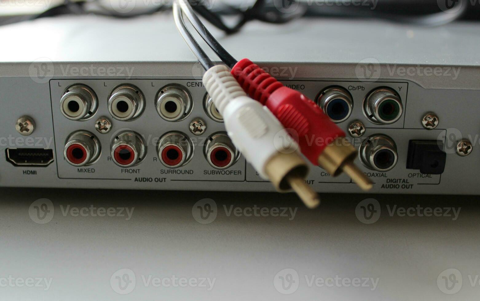 RCA cable hangs from the top cover of the DVD player against the background of a panel with slots for connecting audio and video devices photo