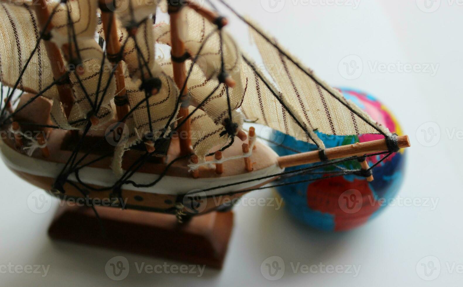 Closeup Top View Of Wooden Masted Ship Model And Blurred Globe Behind Bowsprit photo