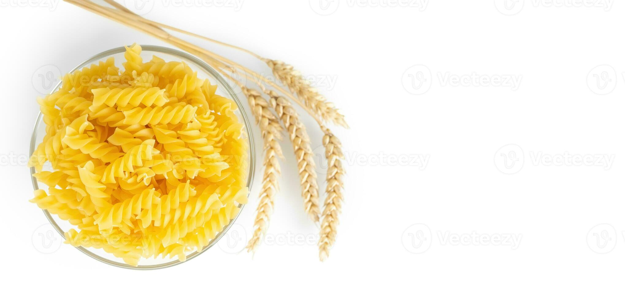 Raw pasta fusilli in bowl and wheat spikelets isolated on white background photo