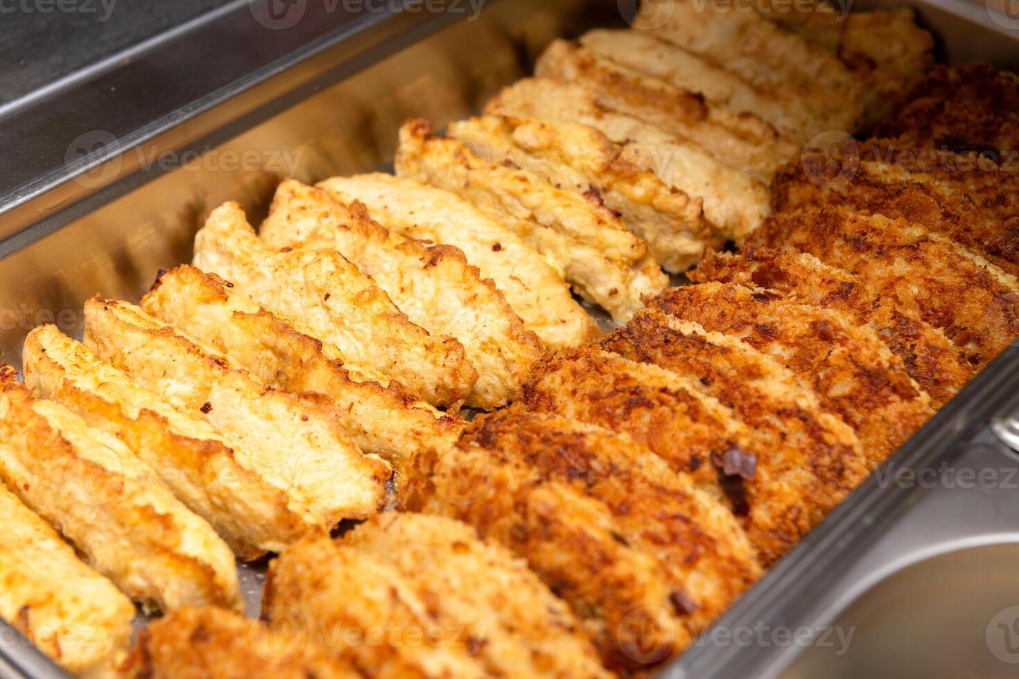 Rows of schnitzels in a metal tray photo