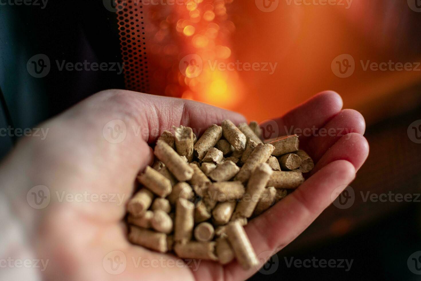 mano participación pellets en frente de el vaso de un estufa con un hermosa fuego foto