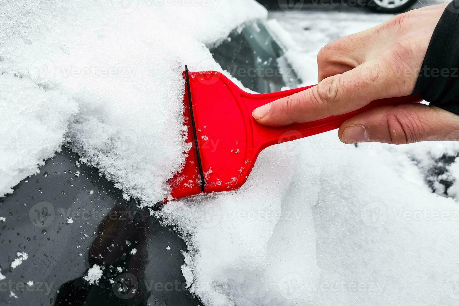 Cleaning the car from snow with a scraper photo