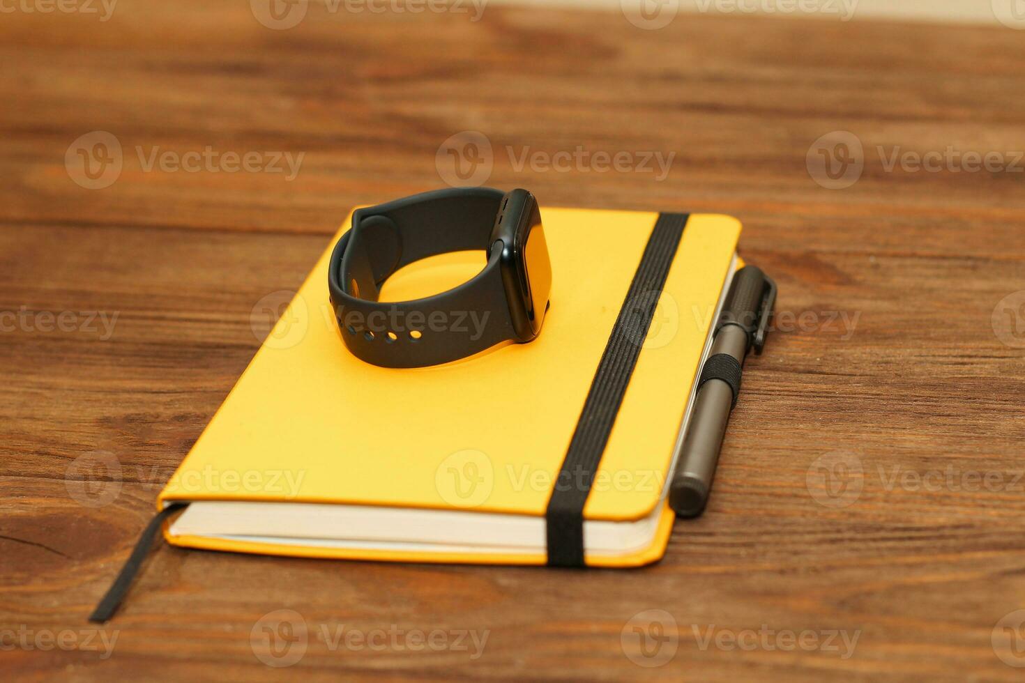 A black technological smart watch lies on a notepad for time management. photo