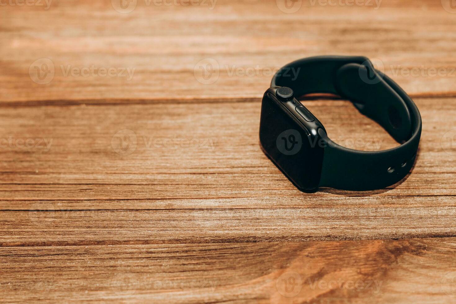 A black technological smart watch lies on a wooden background photo