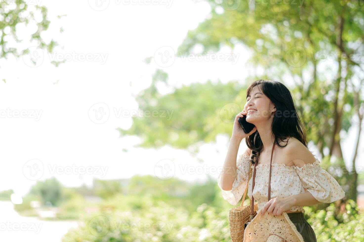 Portrait of asian young woman traveler with weaving hat, basket, mobile phone and camera on green public park background. Journey trip lifestyle, world travel explorer or Asia summer tourism concept. photo