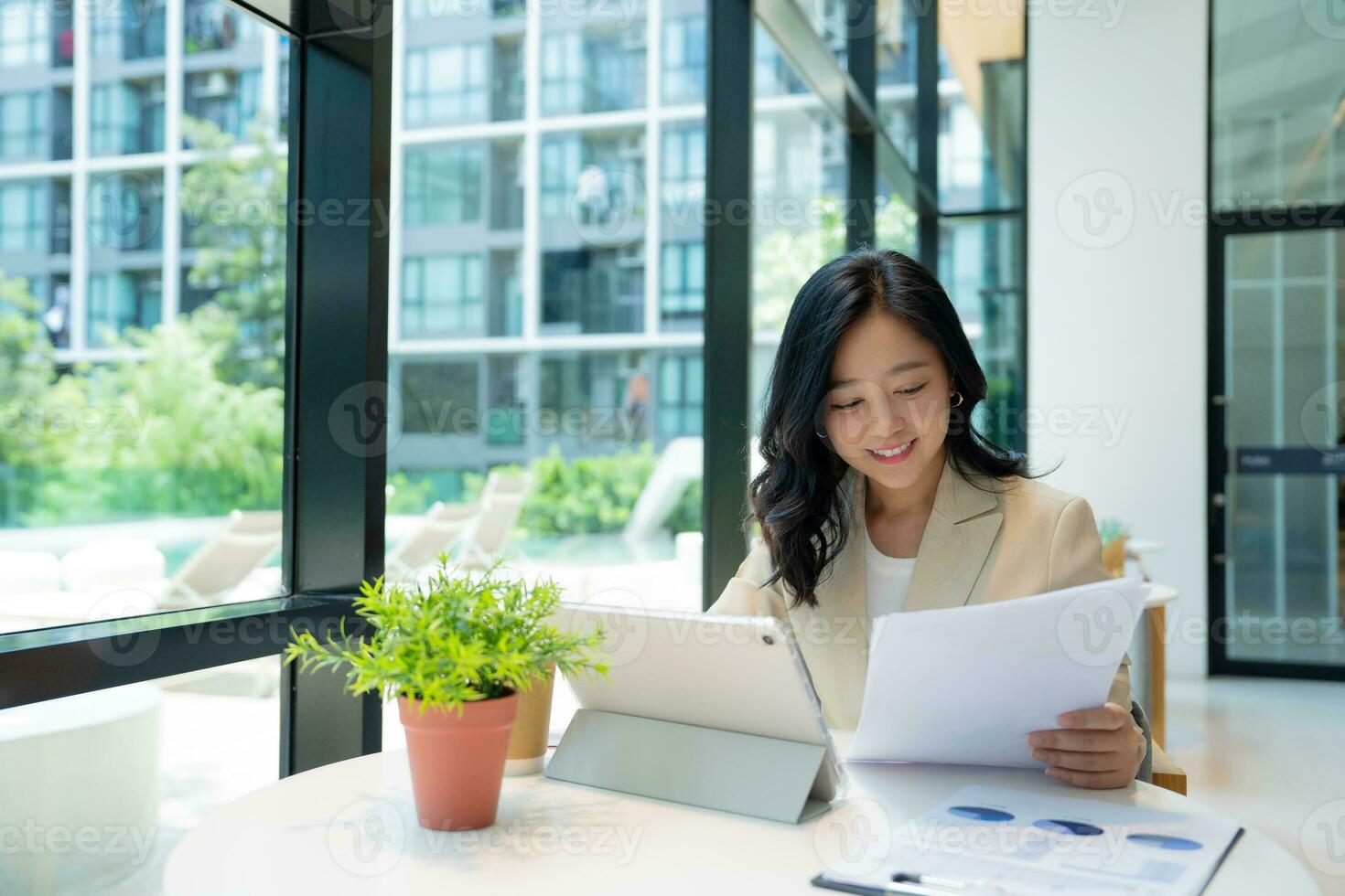 Attractive young Asian female entrepreneur uses a laptop computer while sitting at a coffee shop in a co-working space. photo