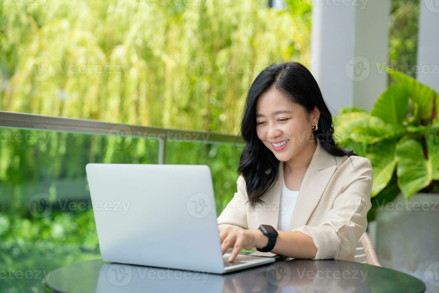 Freelance Asian business woman working using laptop computer. She sits and works in the public garden. photo