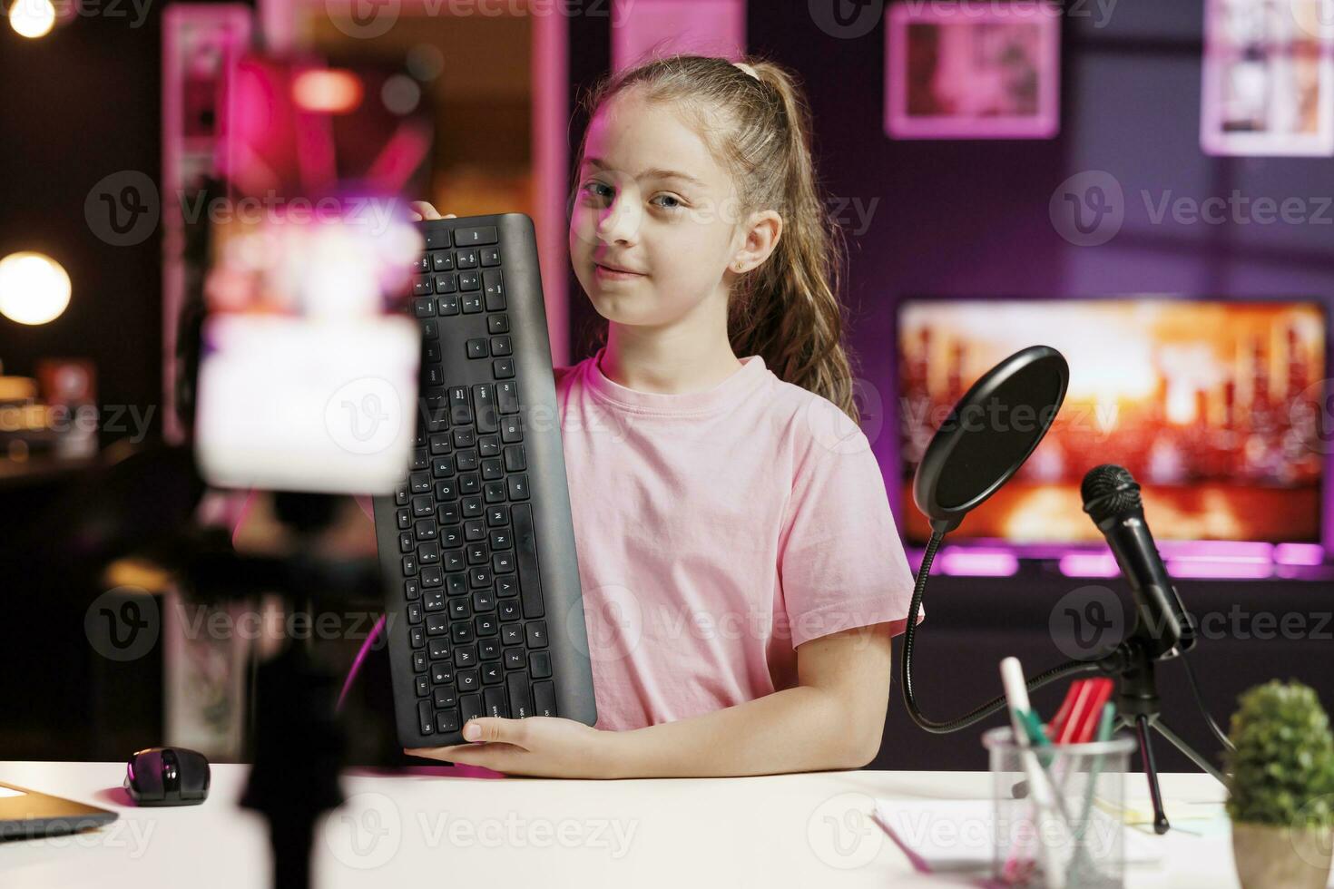 Smiling kid showing viewers mechanical keyboard received from sponsoring brand to promote it. Young online show host advertising wireless gaming computer peripheral from partnering company photo