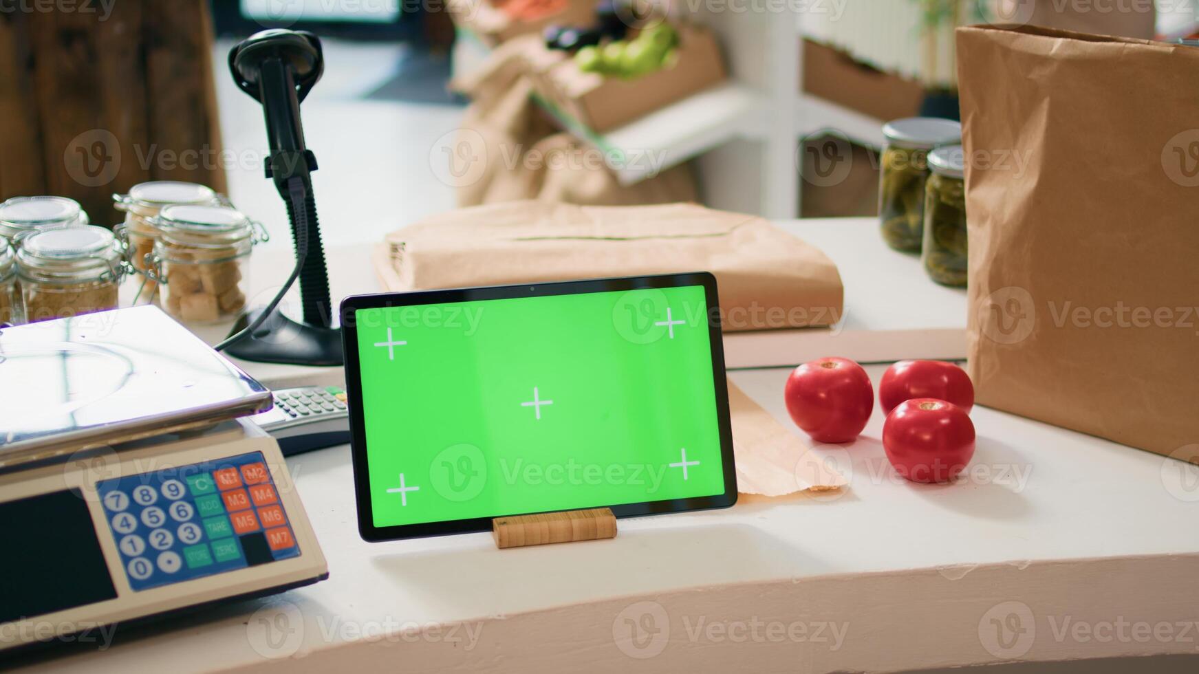 Greenscreen on device at cash register in local bio supermarket with locally grown produce, seller using isolated chromakey display on tablet. Business owner shows blank mockup screen. photo