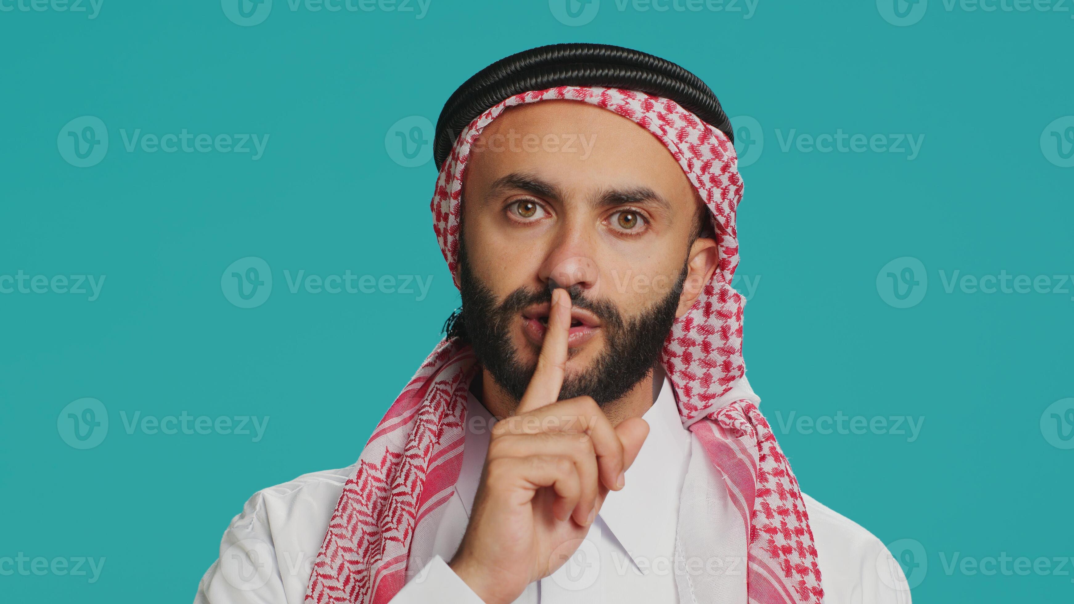 On camera, arabic person makes quiet signal with finger over lips