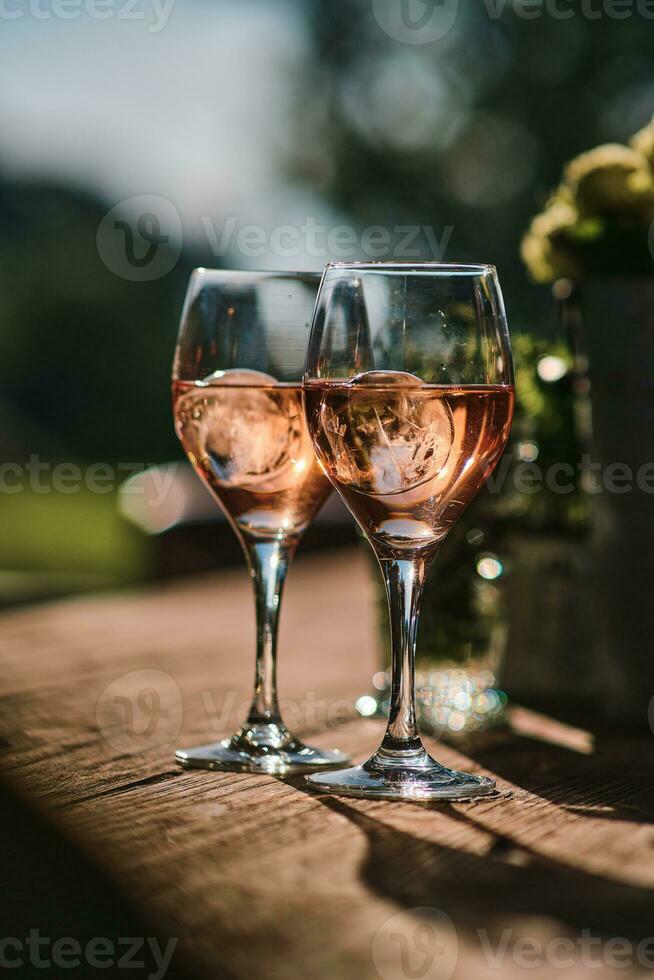 dos lentes de Rosa vino en de madera mesa foto