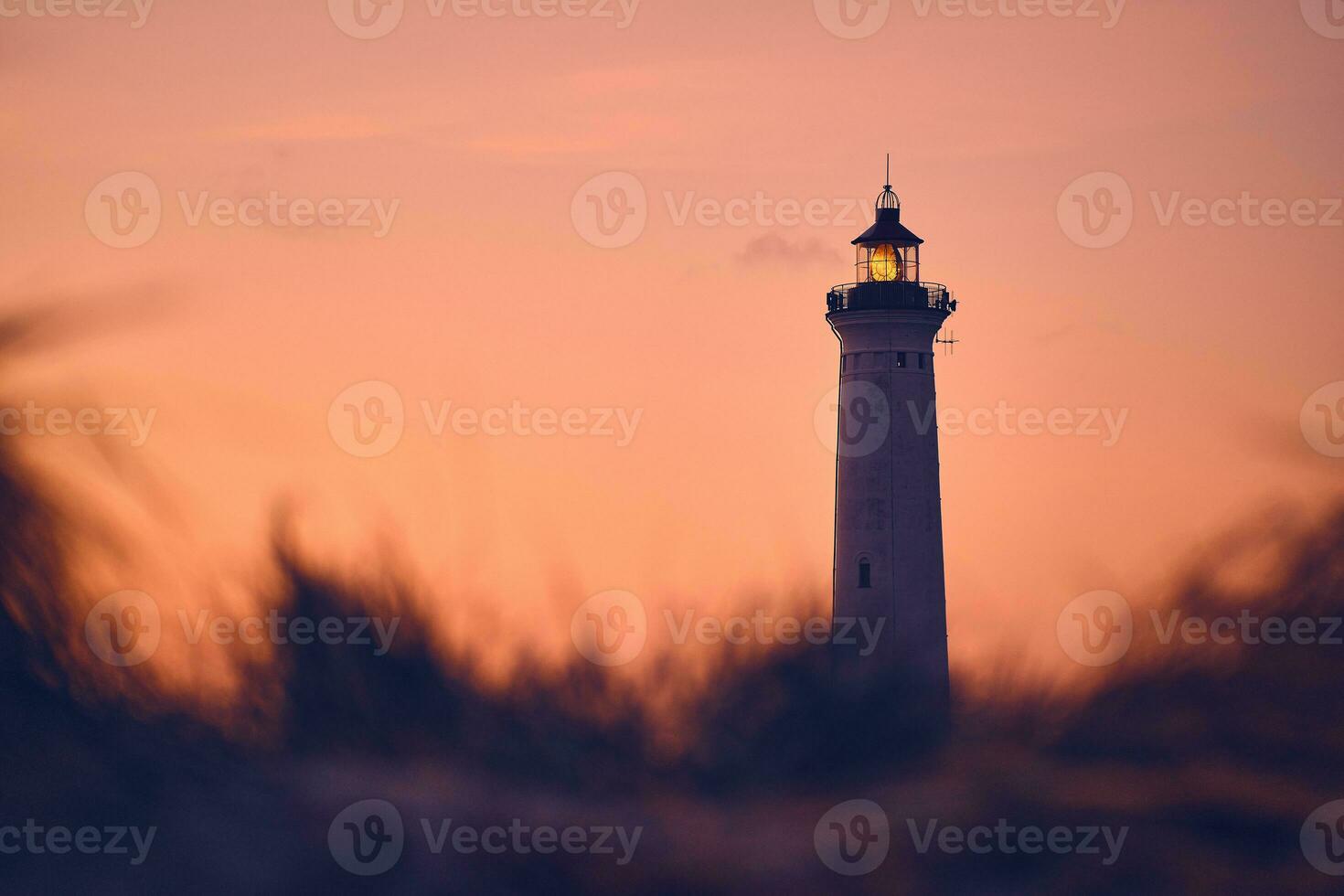 Lighthouse in warm morning glow above the dunes photo