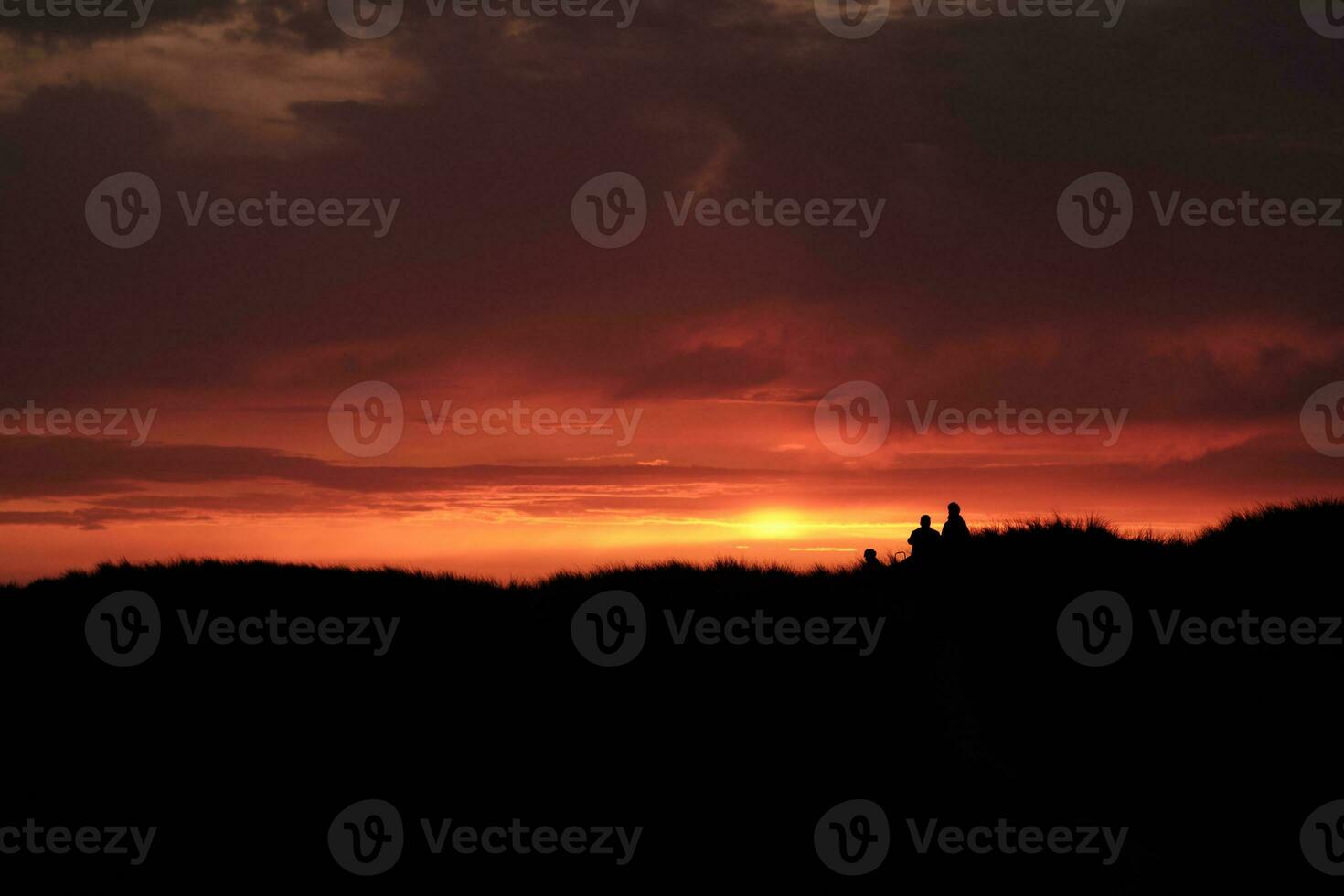 silueta de personas en pie en parte superior de el dunas a puesta de sol foto