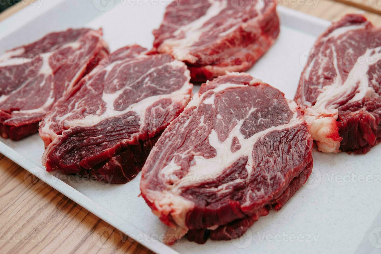 Aged beef for cooking steak in a cooking class. Raw beef and greens, close-up. photo