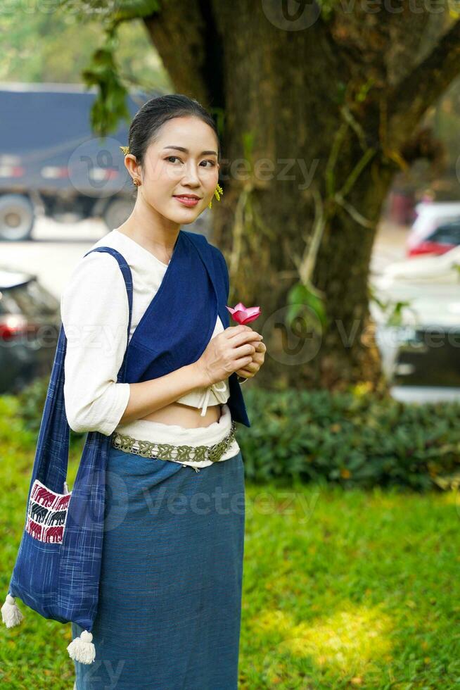 Portrait of Beautiful rural Thai woman wear Thai northern traditional dress acting for photo shoot in public park