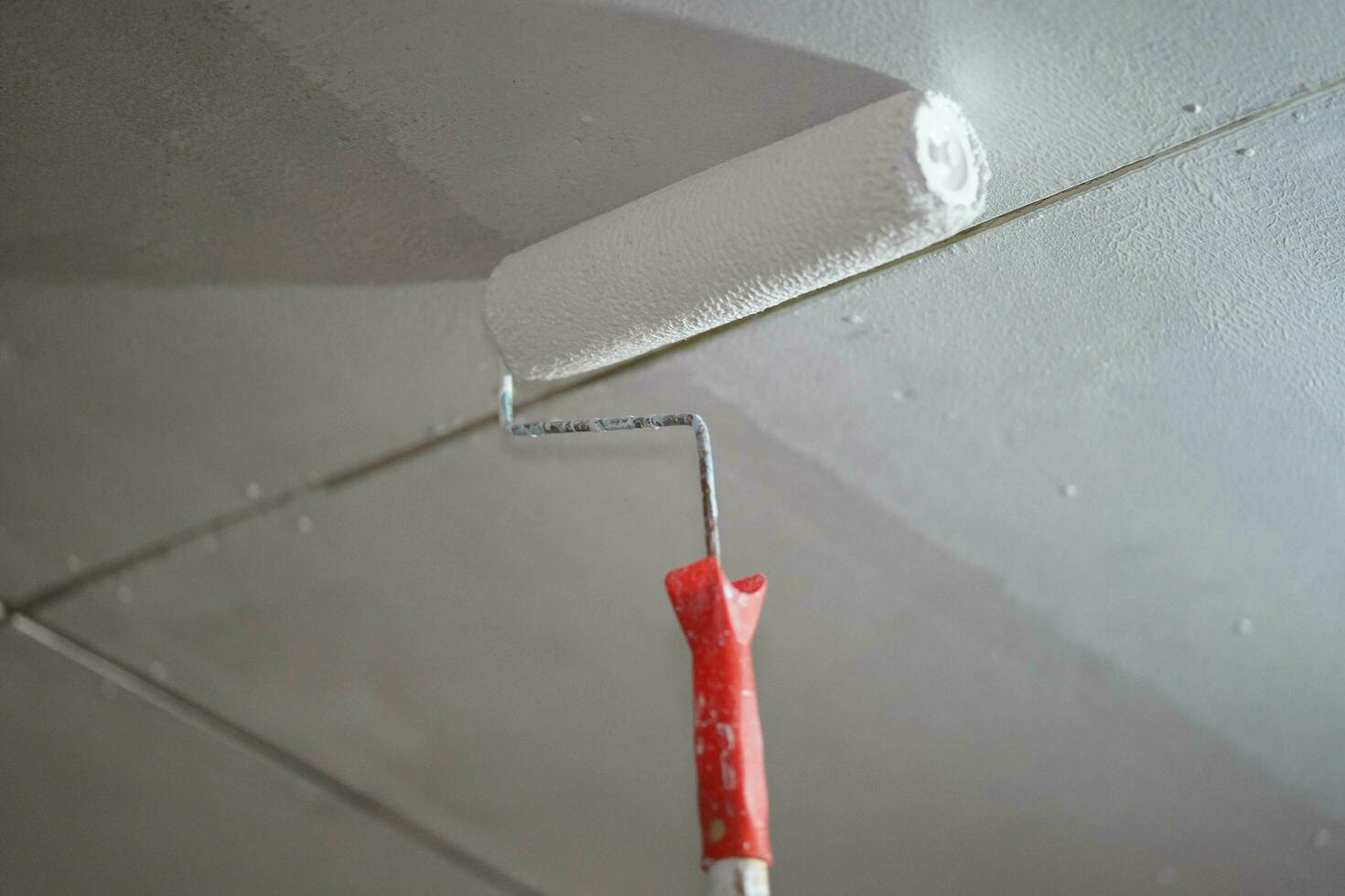 Closeup a painted roller is painted white on the ceiling in renovation of old house. photo