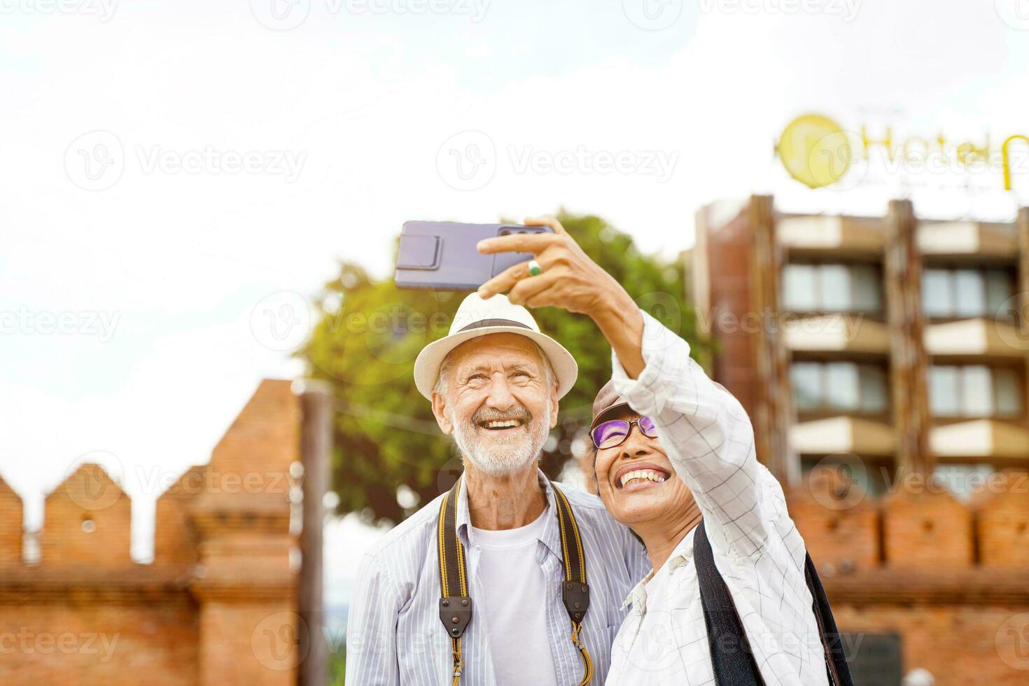 de cerca americano mayor turista hombre con su excursión guía tomar un foto selfie en borroso de ciudad portón antecedentes. mayor turista concepto