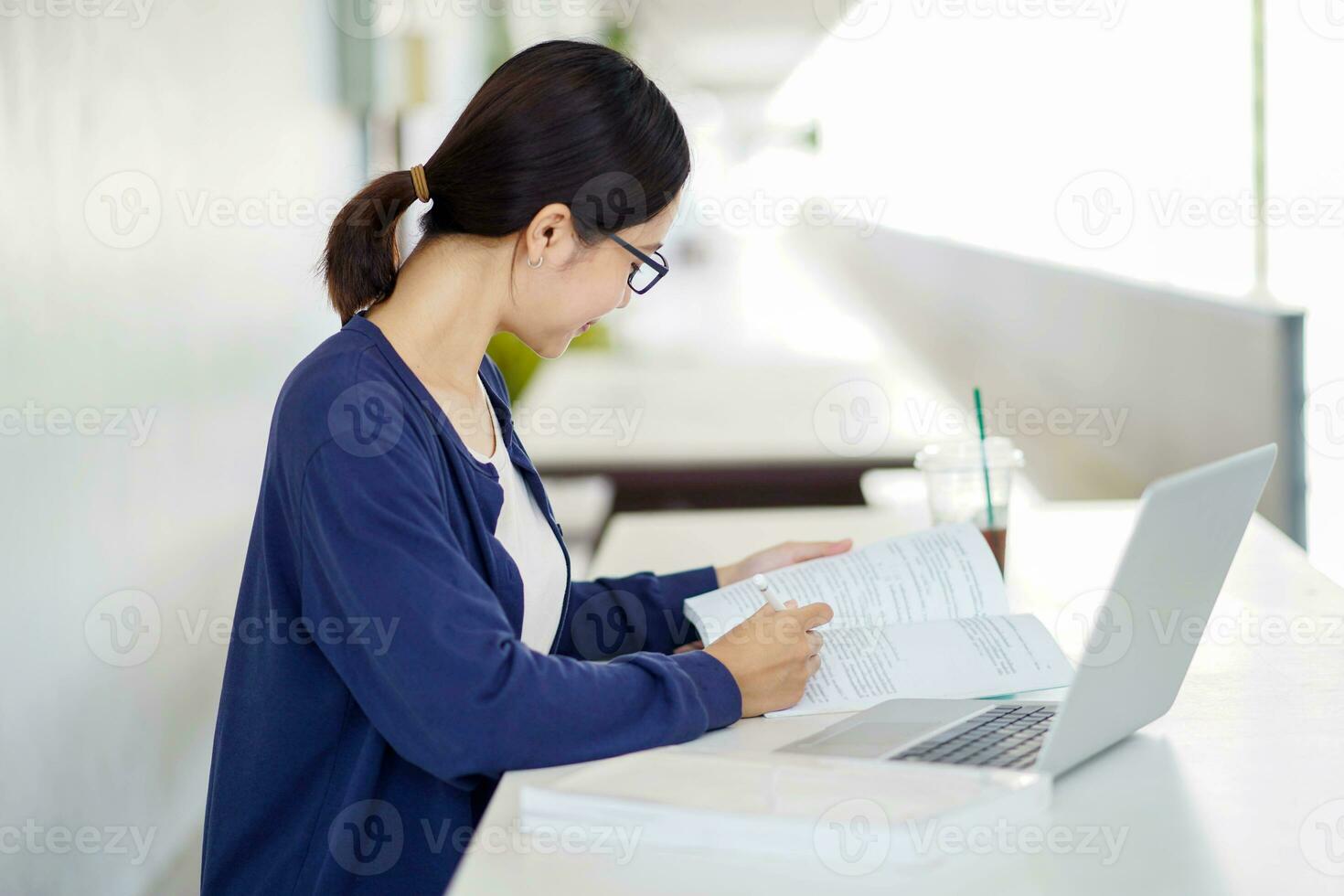 Closeup Asian young female student in casual cloth reading a textbook for the exam with laptop at school building and blurred background. Asian school concept. photo