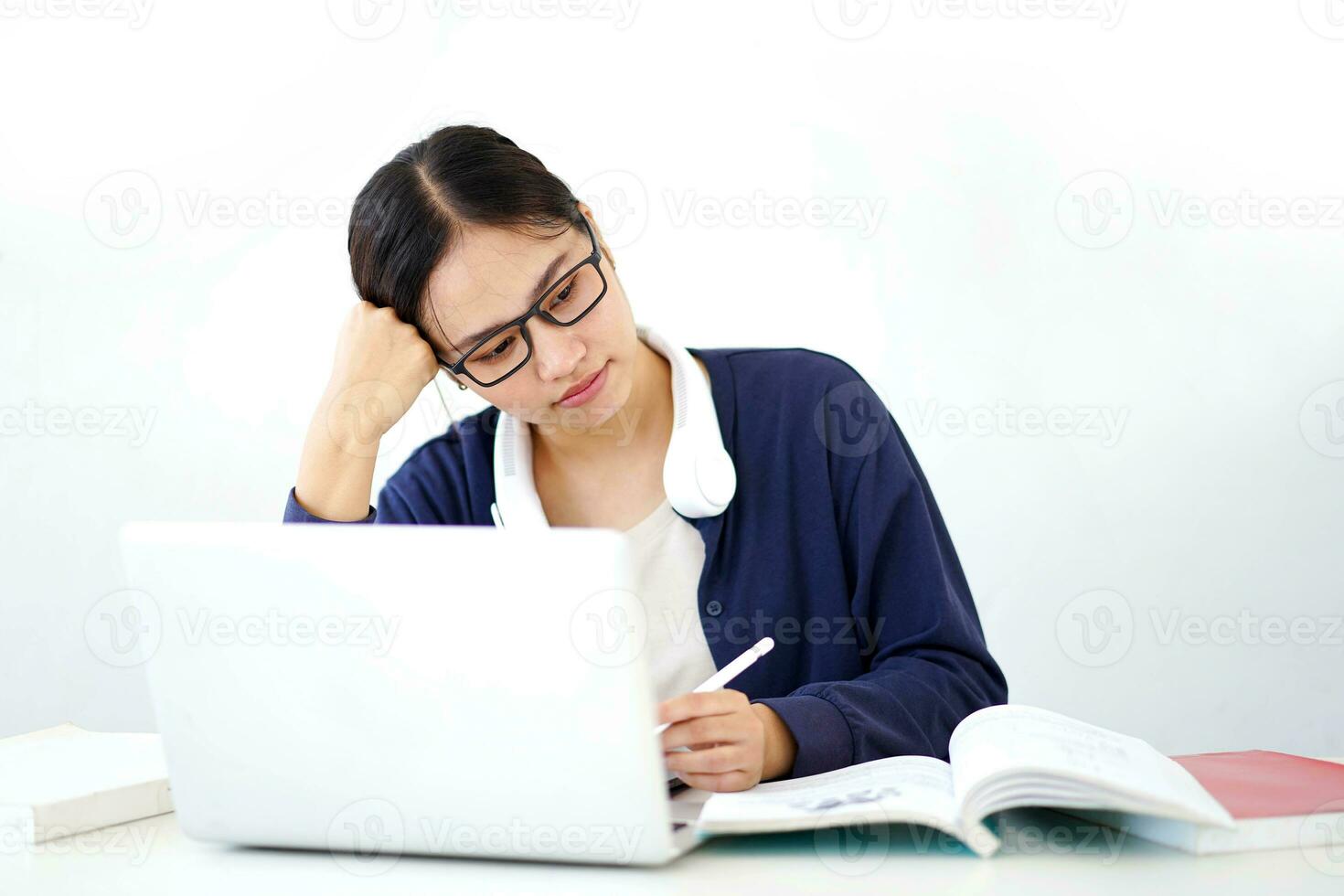 Closeup Asian young female student in casual cloth shows boredom in doing reports or homework with laptop on white gradient background. Asian school concept. photo
