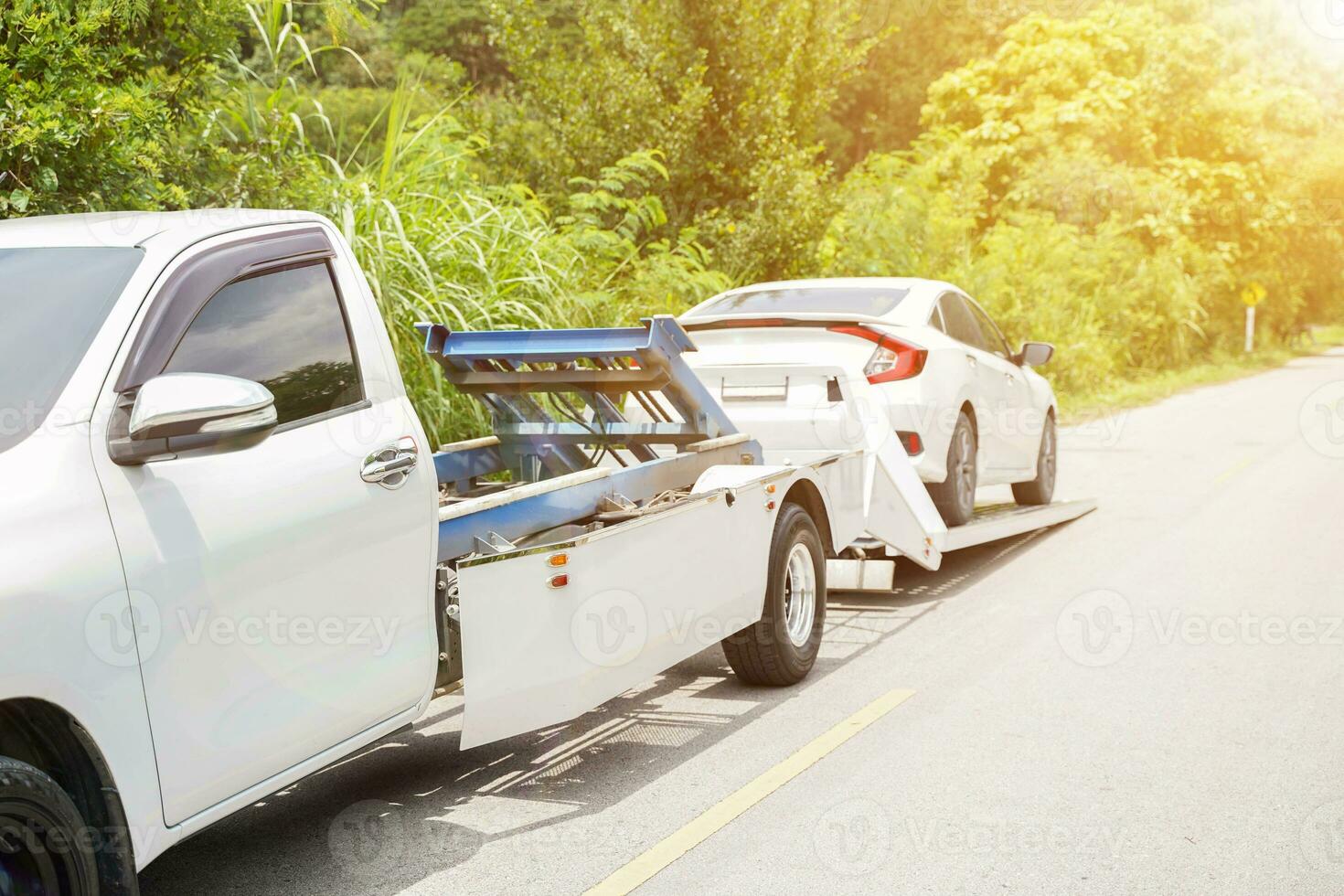 Closeup damaged car truck slides and the white car in the accident on local road with sun flare and green plants background. photo