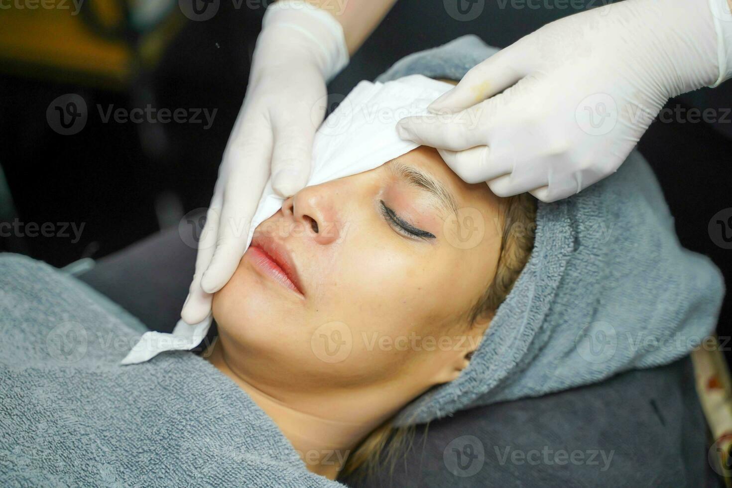 Closeup cosmetologists cleaning the face of Asian beauty woman before making face spa and facial mask. photo