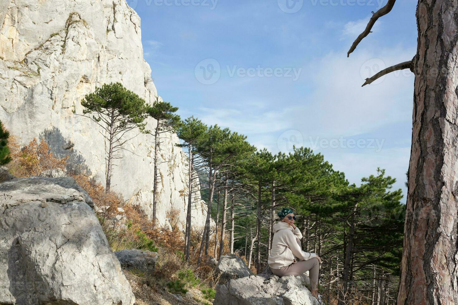 young woman hiker sits on a stone on a background of mountains photo