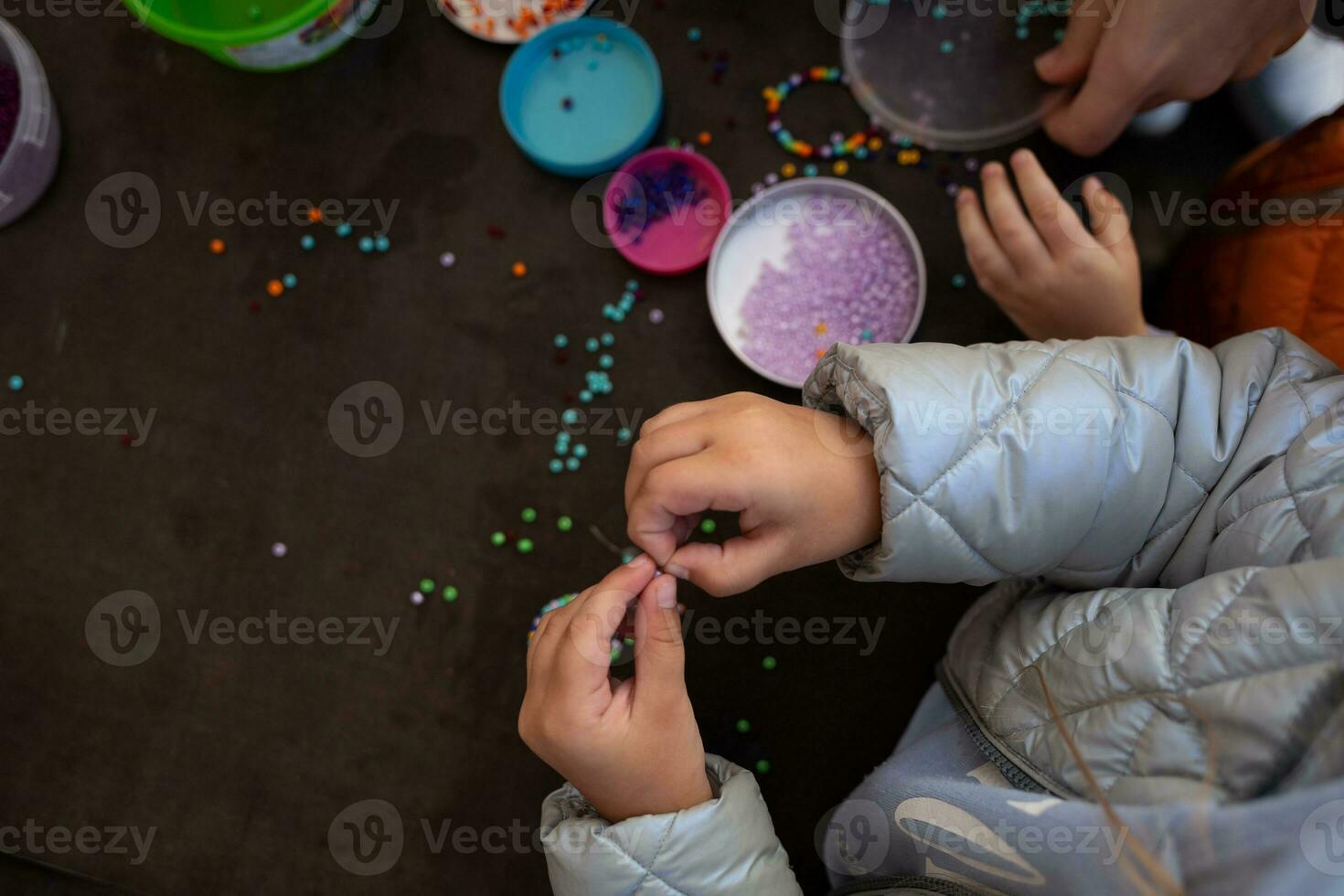 little children's hands weave a bead bracelet close-up shot photo