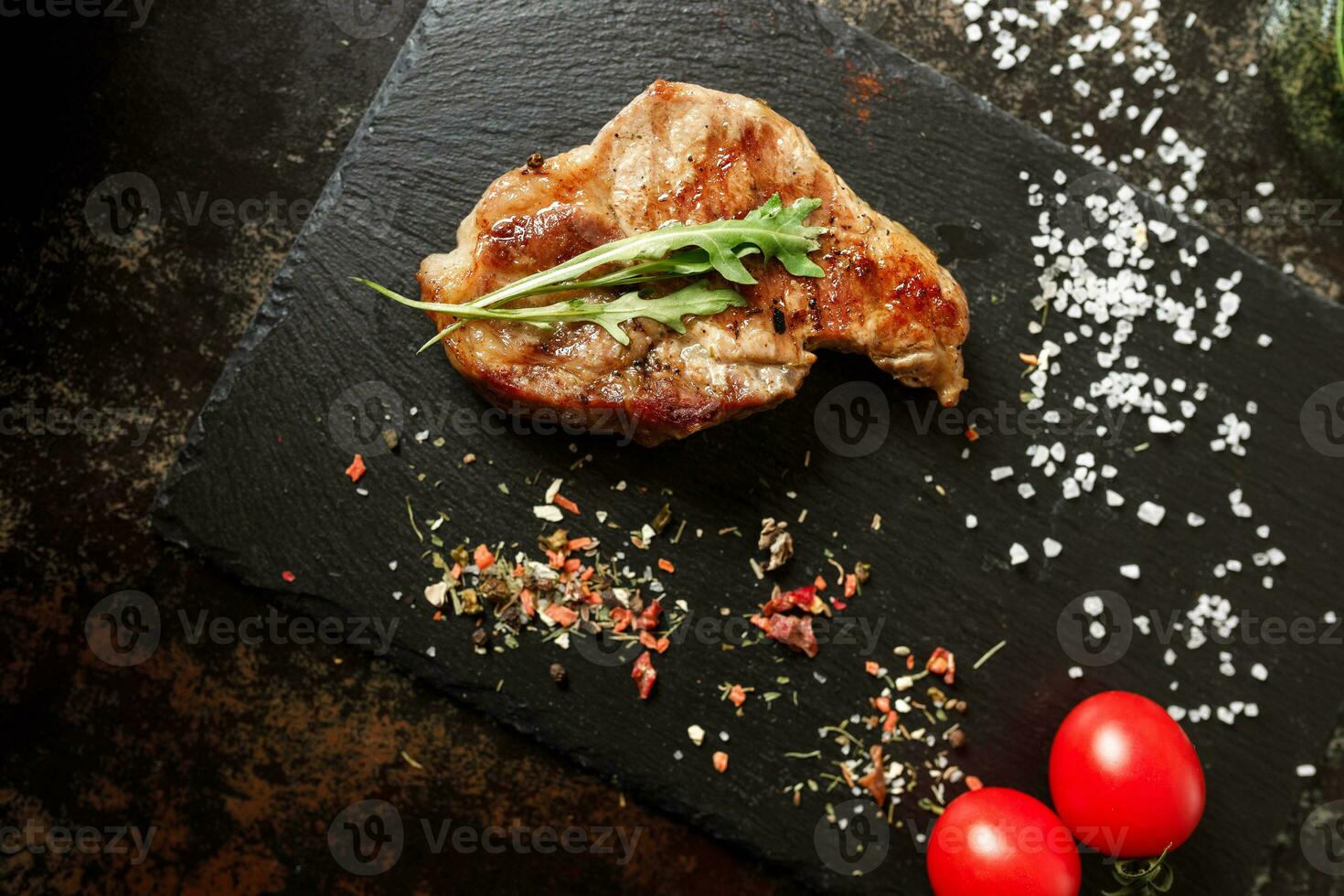 pan-fried pork with spices on a dark stone background photo