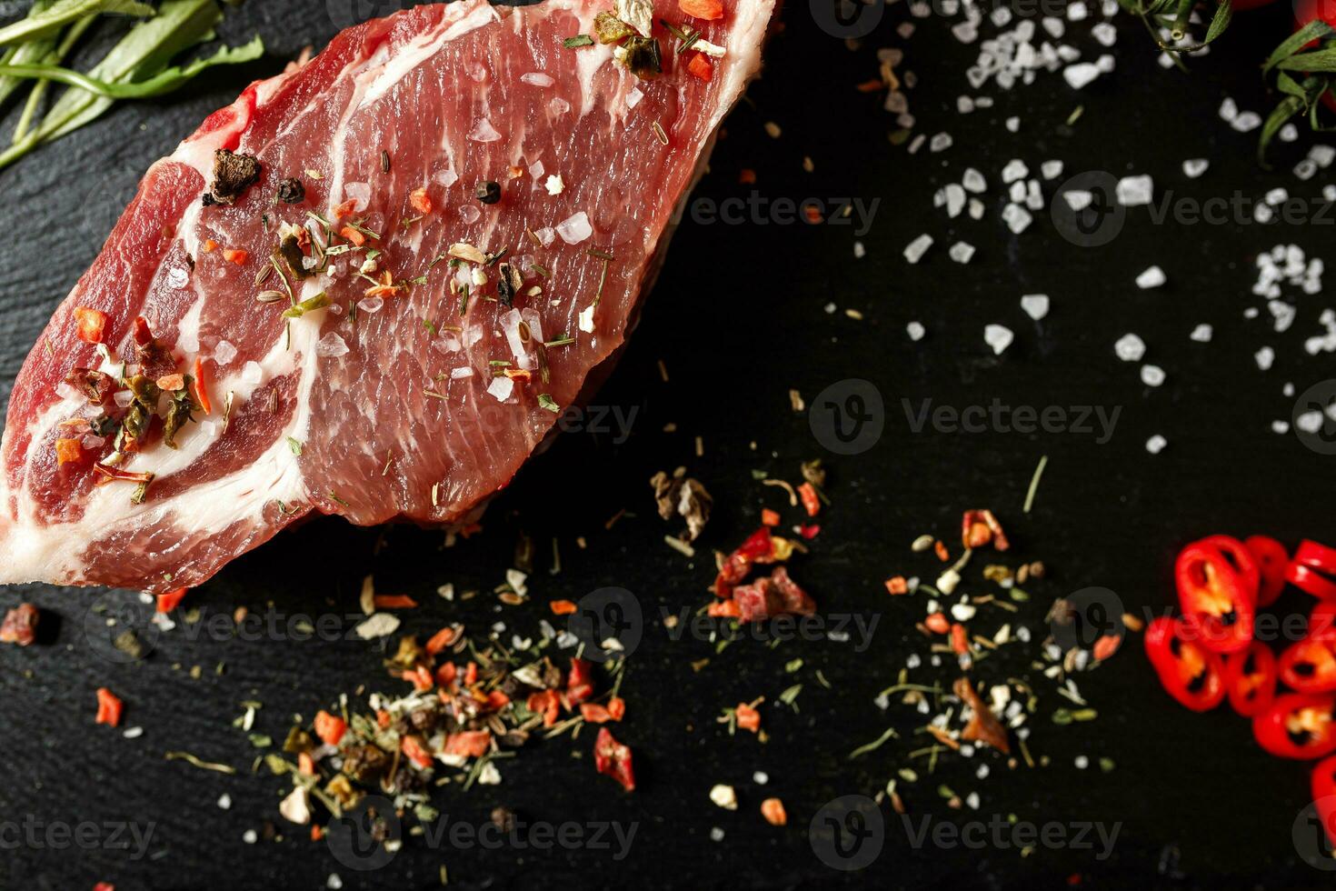 cerdo crudo con especias para cocinar al fuego o al horno sobre un fondo de piedra oscura foto