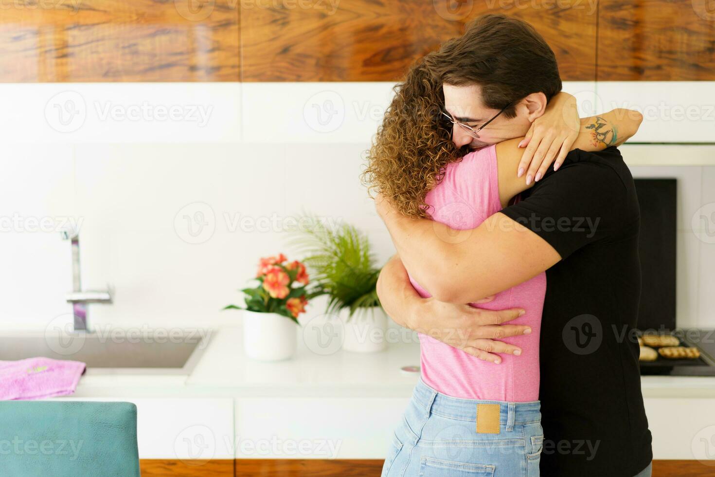 contento Pareja en pie en cocina y abrazando cada otro en luz foto