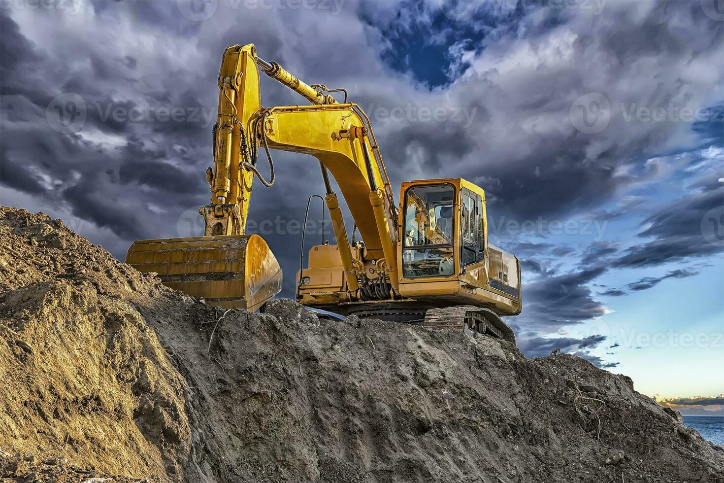 A stopping yellow excavator at an incredibly beautiful sunset photo