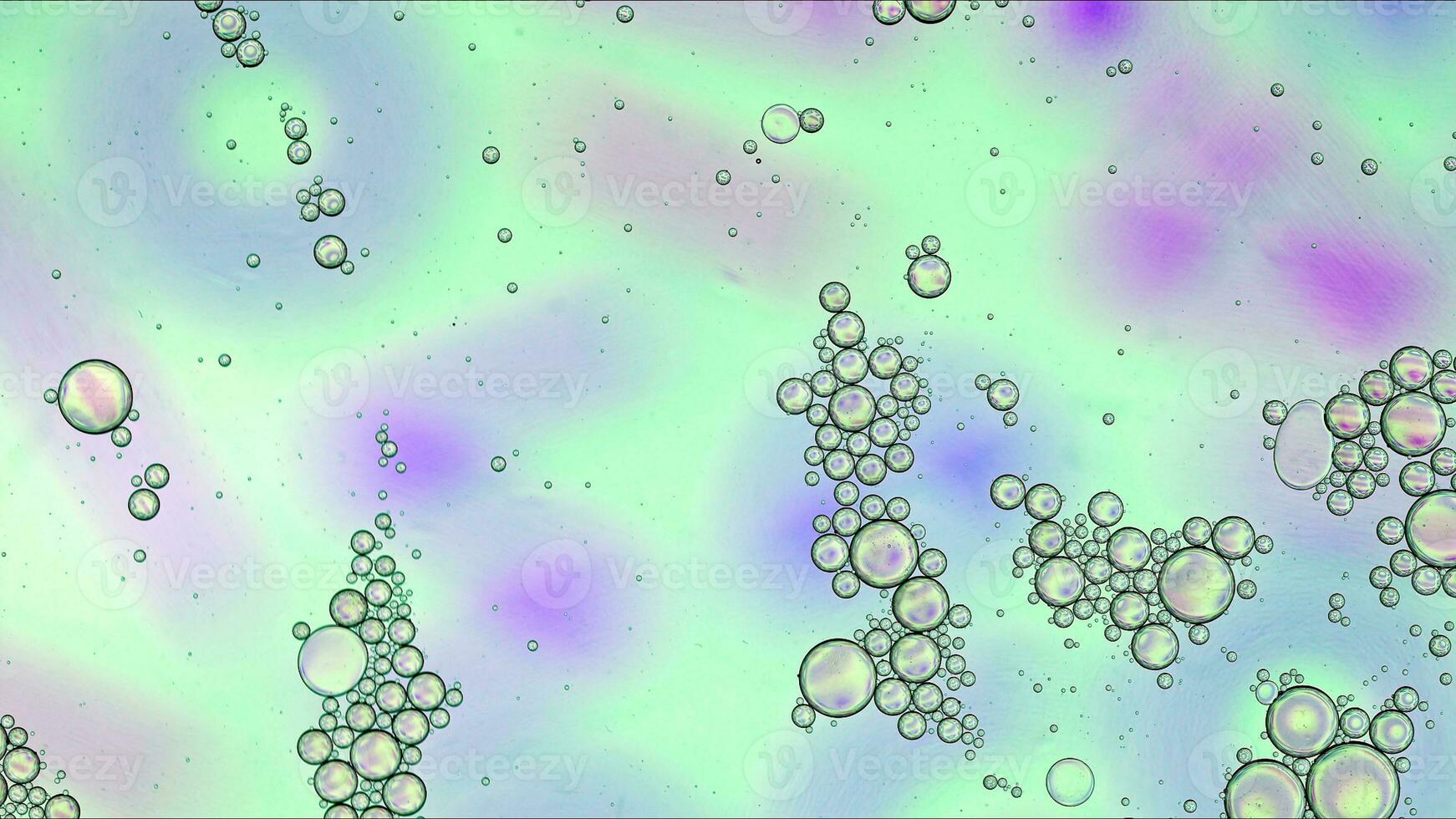 El aceite de comida colorido abstracto cae burbujas y esferas que fluyen en la superficie del agua foto