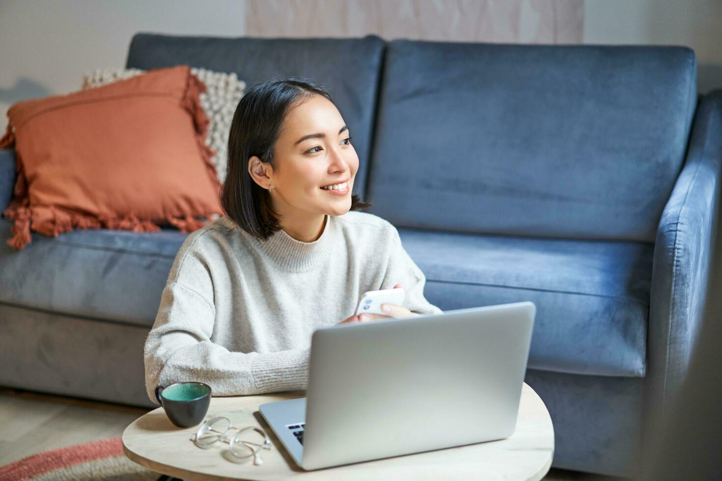 trabajo desde hogar, Lanza libre y e-learning concepto. joven mujer estudiando, sentado en frente de computadora portátil, trabajando en remoto, lugar de trabajo en vivo habitación foto