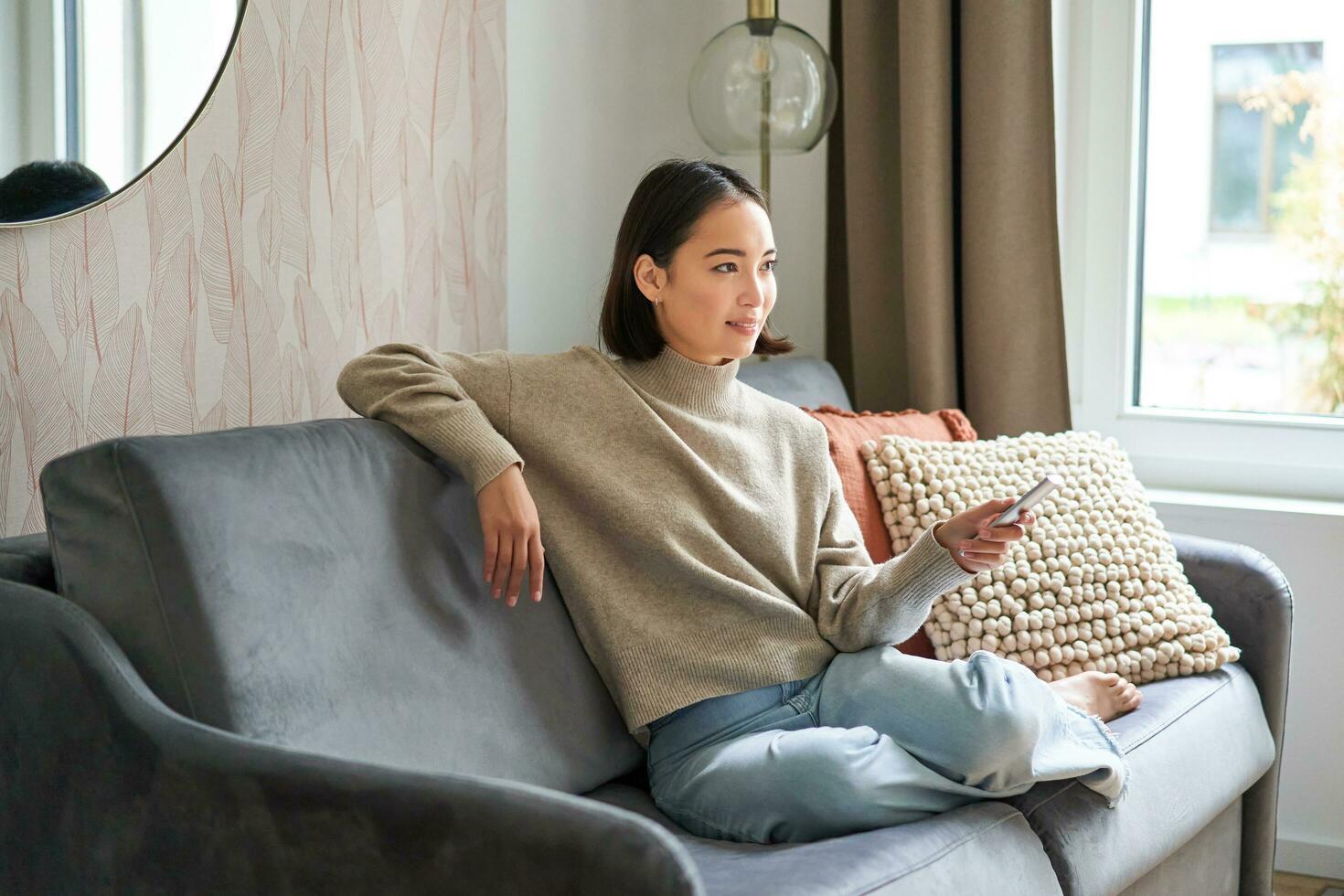 Portrait of modern woman sitting at home with remote, relaxing on weekends, watching tv television and smiling photo