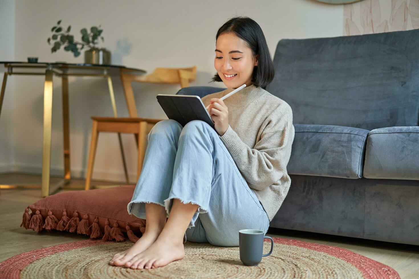 Portrait of creative young woman drawing on digital tablet with pen, drinking coffee, working from home, plan and design new project photo