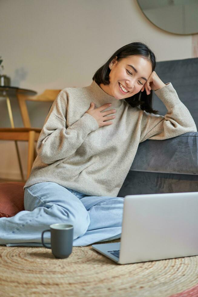 Vertical shot of beautiful asian woman, student sitting at home and studying remotely, elearning with laptop photo