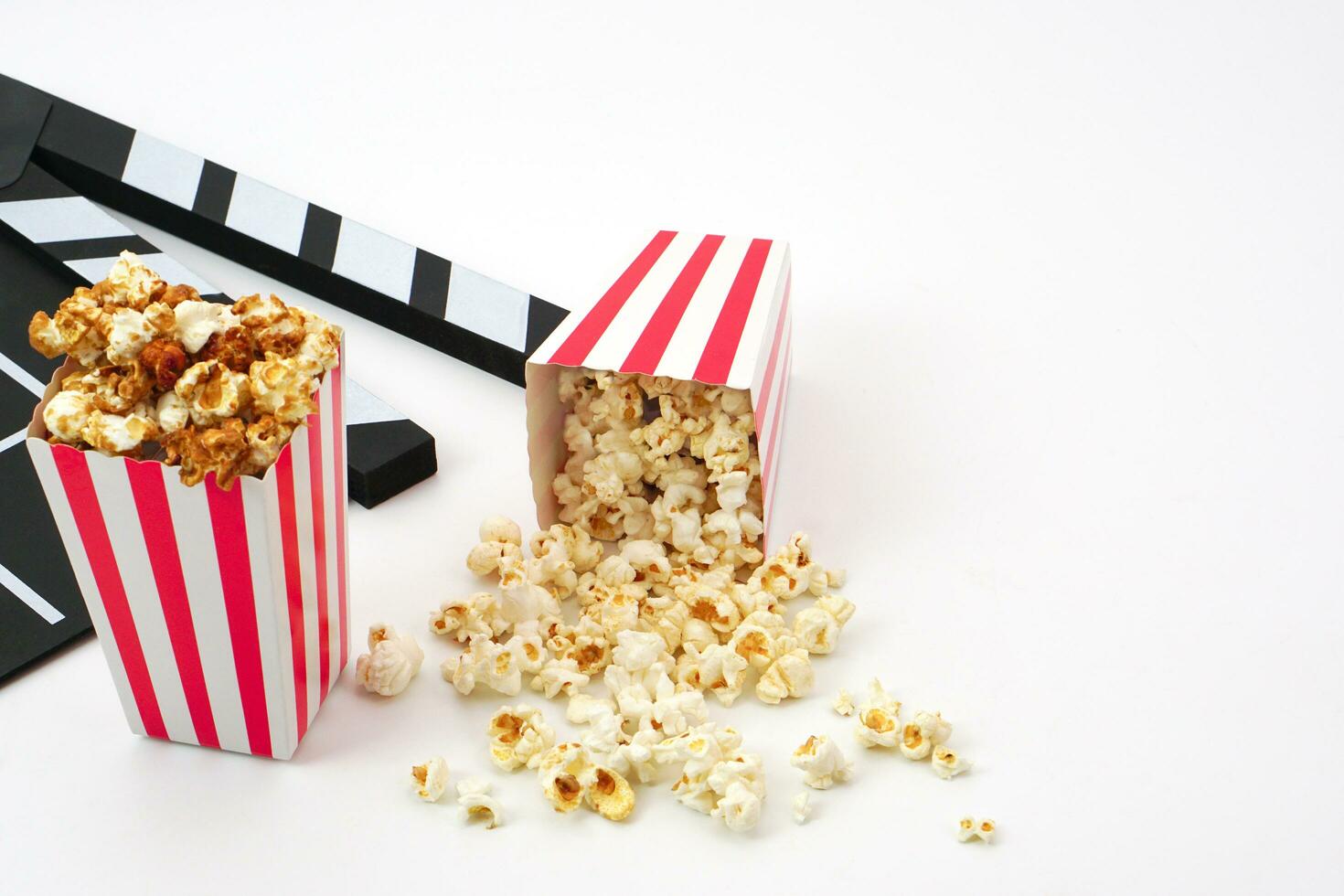 Clapperboard or movie slate black color with popcorn on white background. Cinema industry, video production and film concept. photo