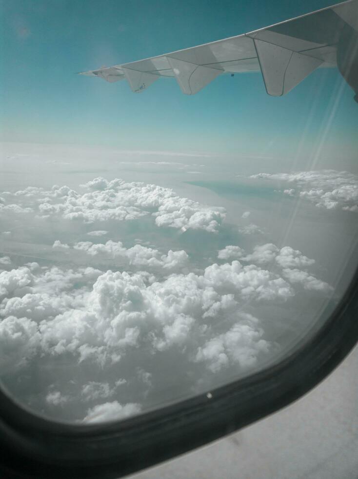 sky and clouds from airplane wing as seen through window of an aircraft photo