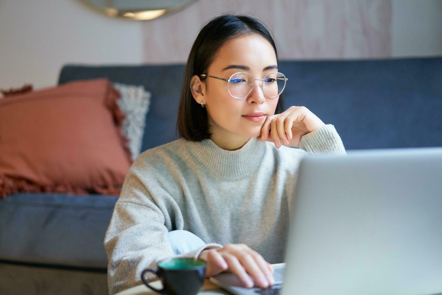 Portrait of smiling asian girl working from home, staying on remote, using laptop, studying on her computer photo