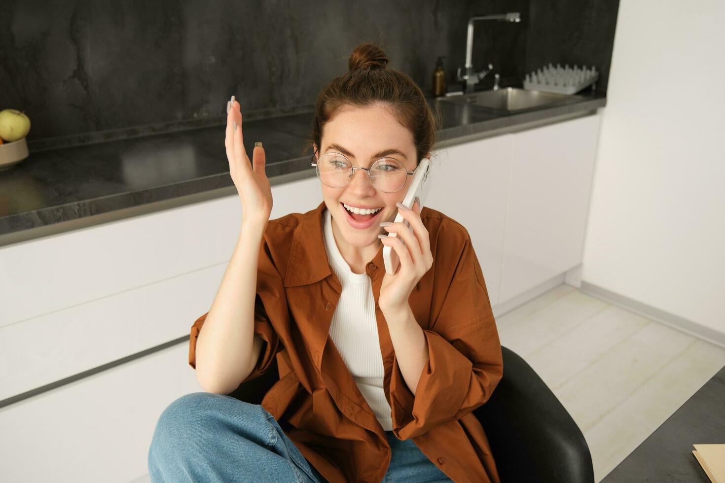 Portrait of happy modern woman, answer phone call and celebrating, looking excited, triumphing from great news, talking on smartphone photo