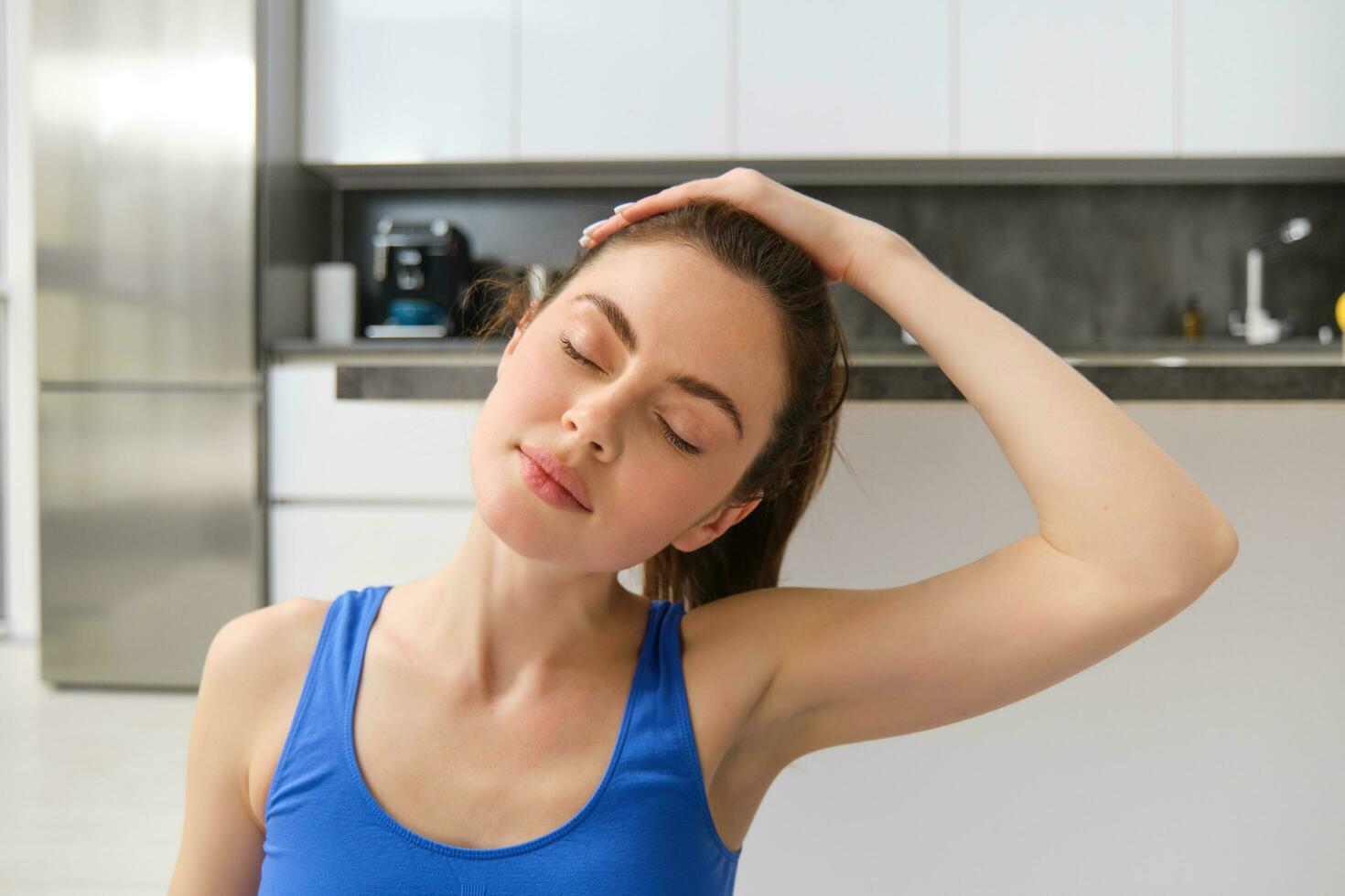 Close-up potrait of fitness woman, does training, workout from home, massaging neck, exercise in living room photo