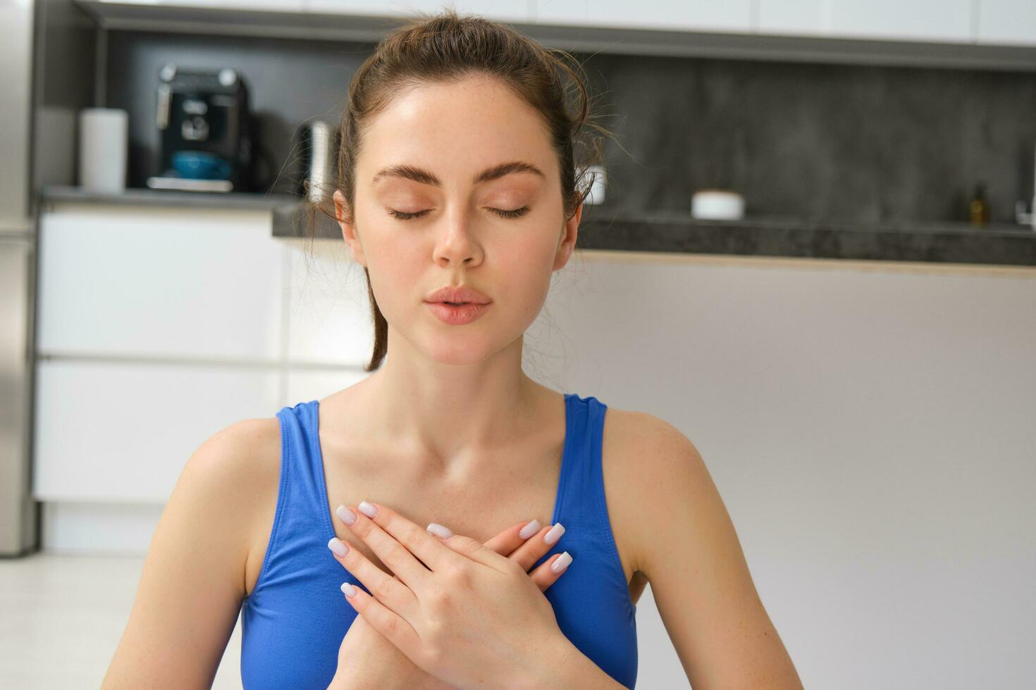 Woman practicing yoga and meditation at home sitting in lotus pose on yoga mat, relaxed with closed eyes. Mindful meditation concept. Wellbeing photo