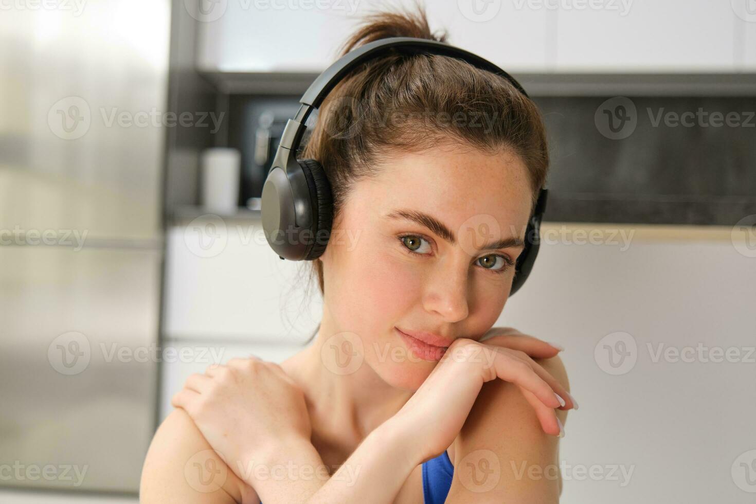 Close up portrait of fitness woman, wearing sportsbra, listening music in headphones, working out at home, doing exercises for fit and healthy body photo