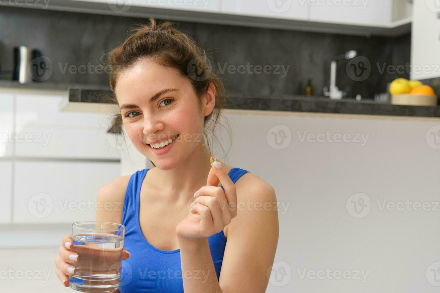 sano estilo de vida y nutrición. joven mujer sonriente, tomando dietético suplemento brotes o vitaminas, pescado petróleo después rutina de ejercicio capacitación, mirando contento a cámara foto