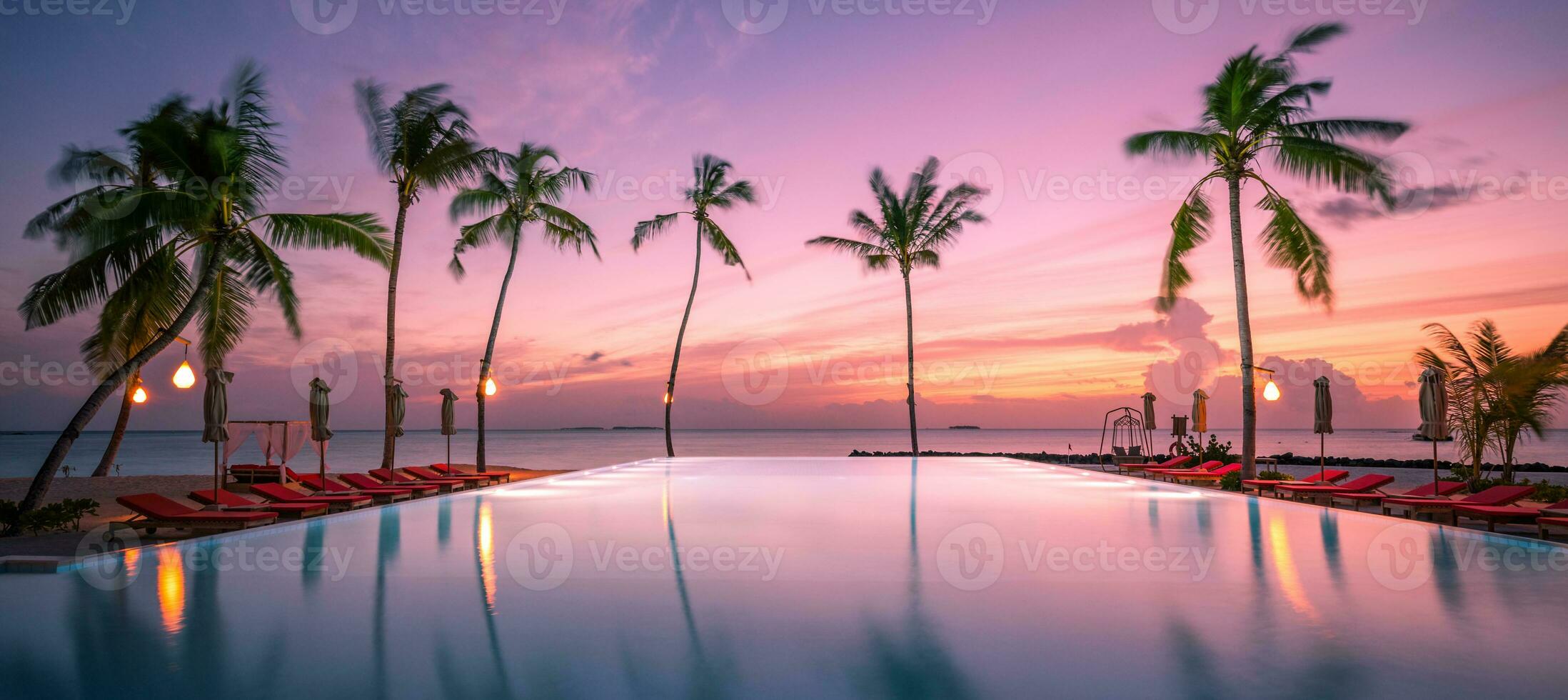 Tropical sunset over outdoor infinity pool in summer seaside resort, beach landscape. Luxury tranquil beach holiday, poolside reflection, relaxing chaise lounge romantic colorful sky, chairs umbrella photo