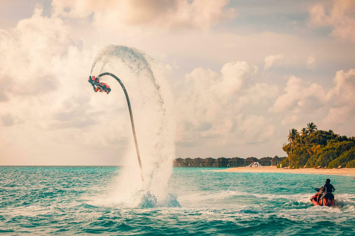 Maldives island sunset. Professional fly board rider doing back flip with tropical resort island background. Sunset sport and summer activity background, fun water sport 08.17.21 - Noonu atoll photo