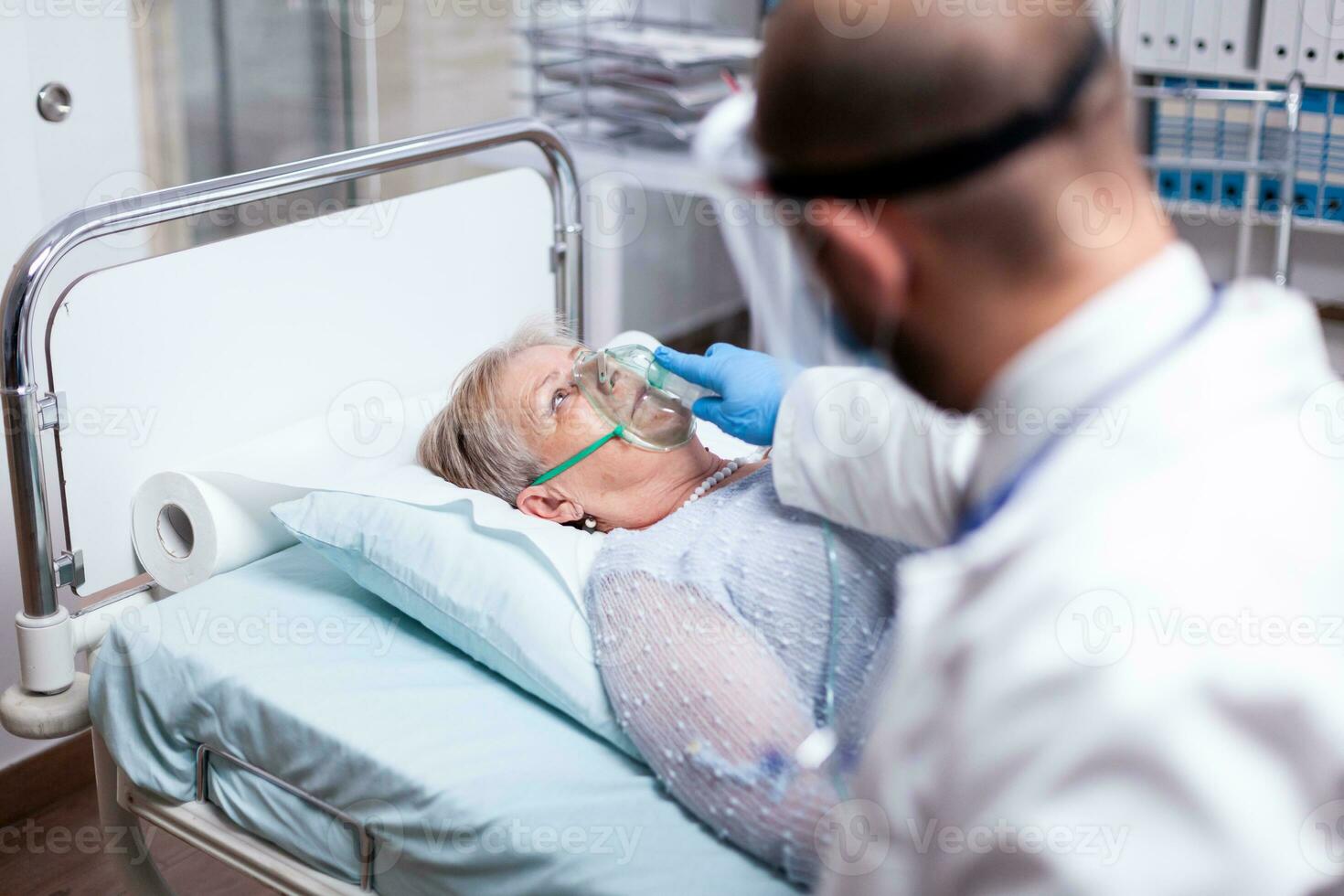 Patient breathing heavily without oxygen mask in emergency hospital room. Doctor helping old woman with pulmonary disease. Medicine medical healthcare system epidemic lungs infection treatment photo