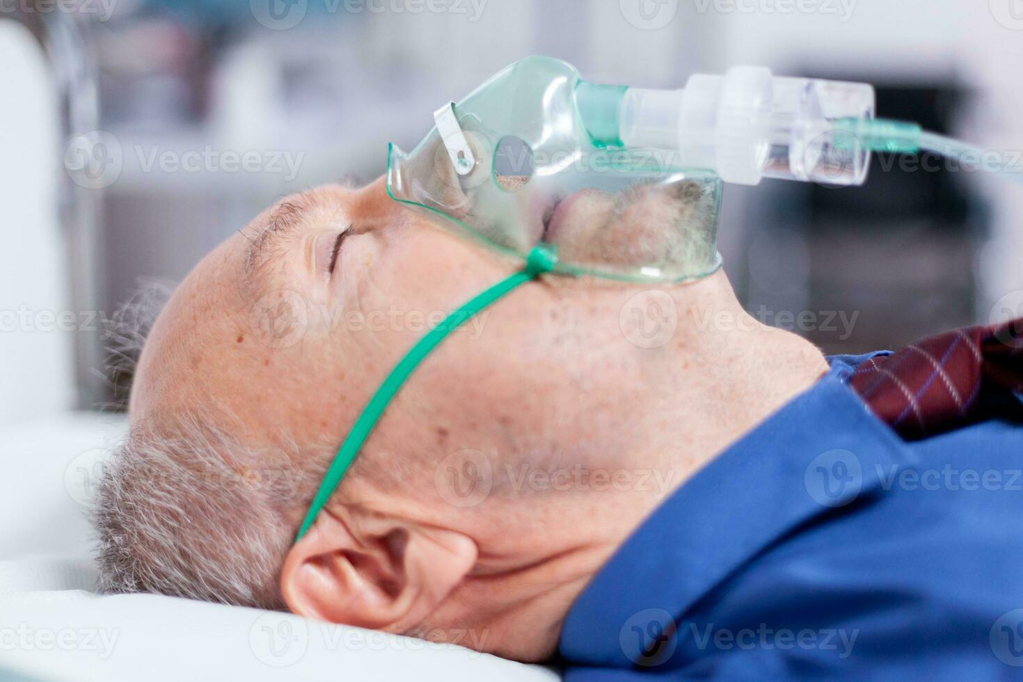 Sick old man with respiratory mask laying on hospital bed after being infected with coronavirus. Medicine medical healthcare system epidemic lungs infection treatment photo