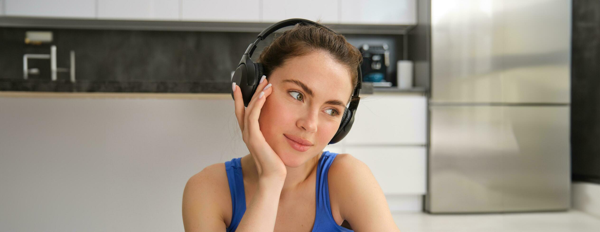 cerca arriba retrato de aptitud mujer, vistiendo sujetador deportivo, escuchando música en auriculares, trabajando fuera a hogar, haciendo ejercicios para ajuste y sano cuerpo foto